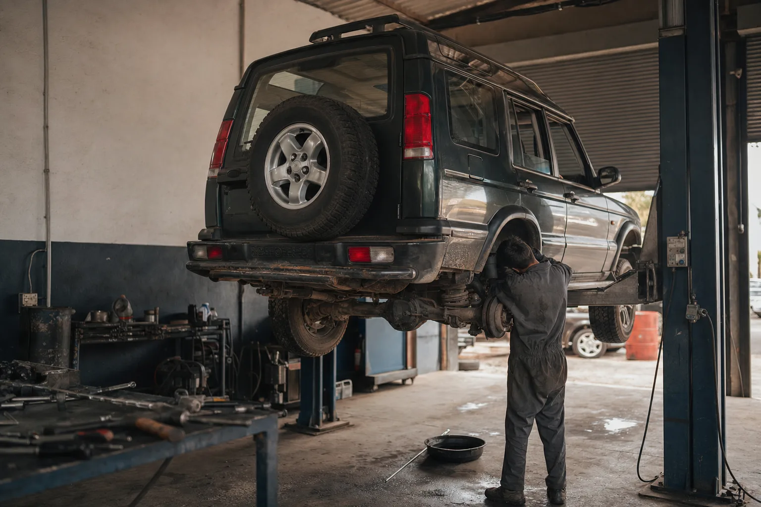 Land Rover Discovery 2 Td5 raised on a workshop lift while a mechanic inspects the rear self-levelling air suspension and chassis